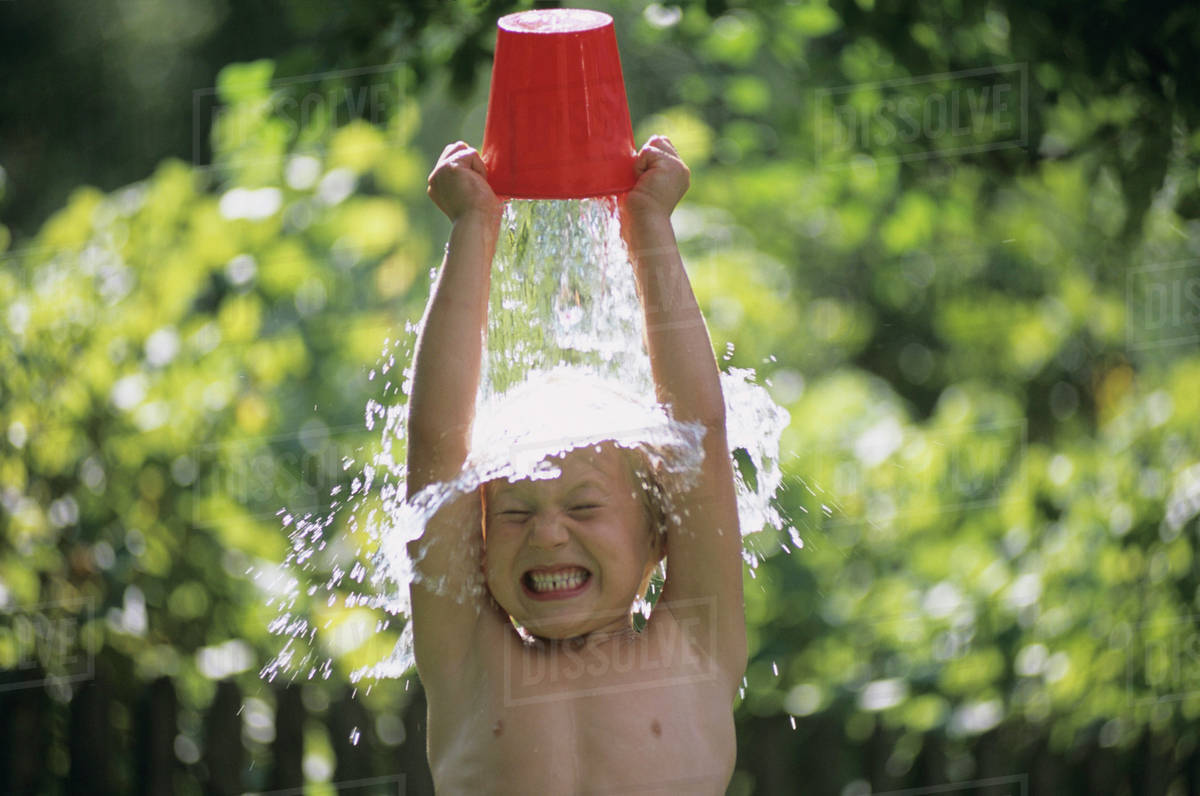Boy pouring water over head, outdoors Stock Photo Dissolve