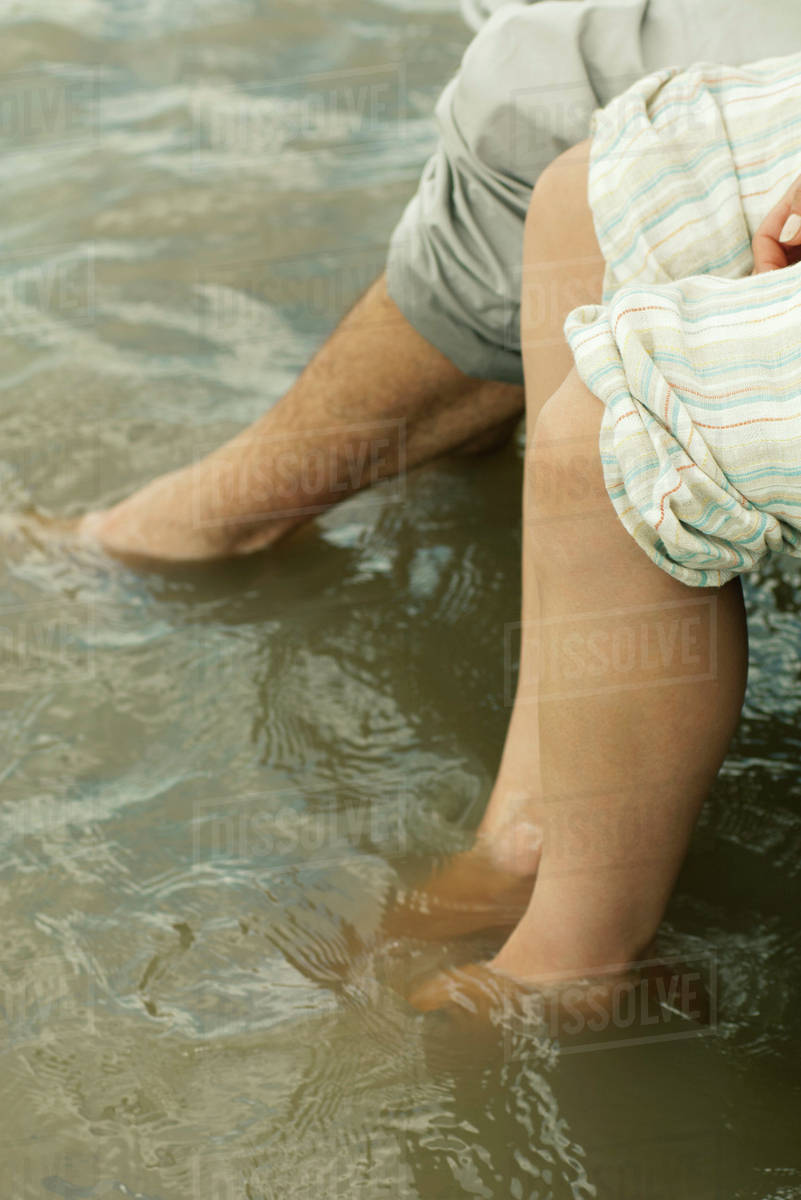 Couple soaking feet in water, cropped Stock Photo Dissolve