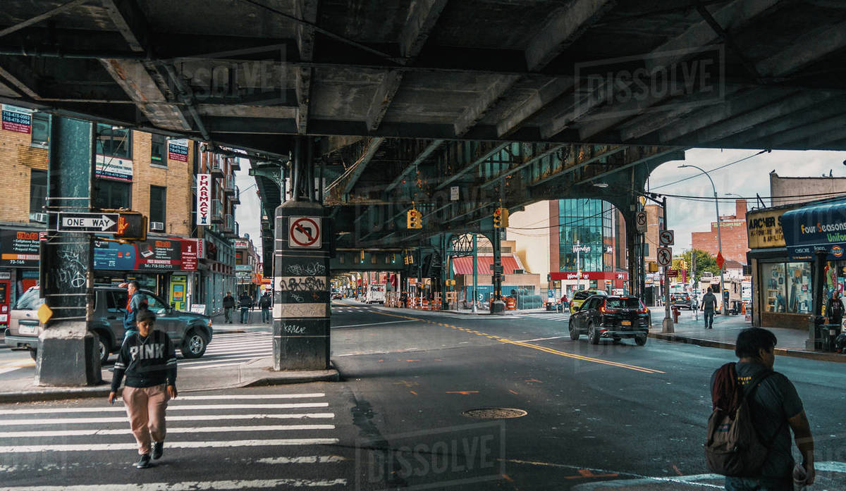 View of people and vehicles moving on street under bridge, New York ...