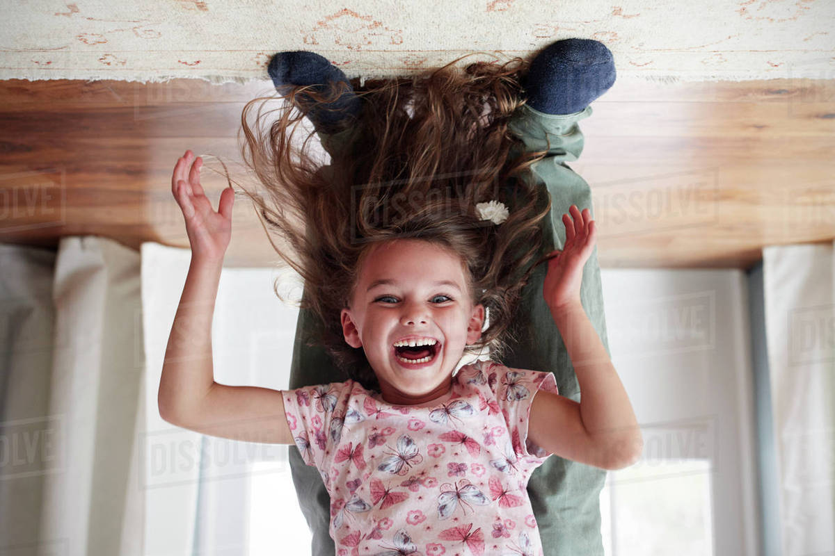 Girl being held upside down by her dad at home, low section Stock