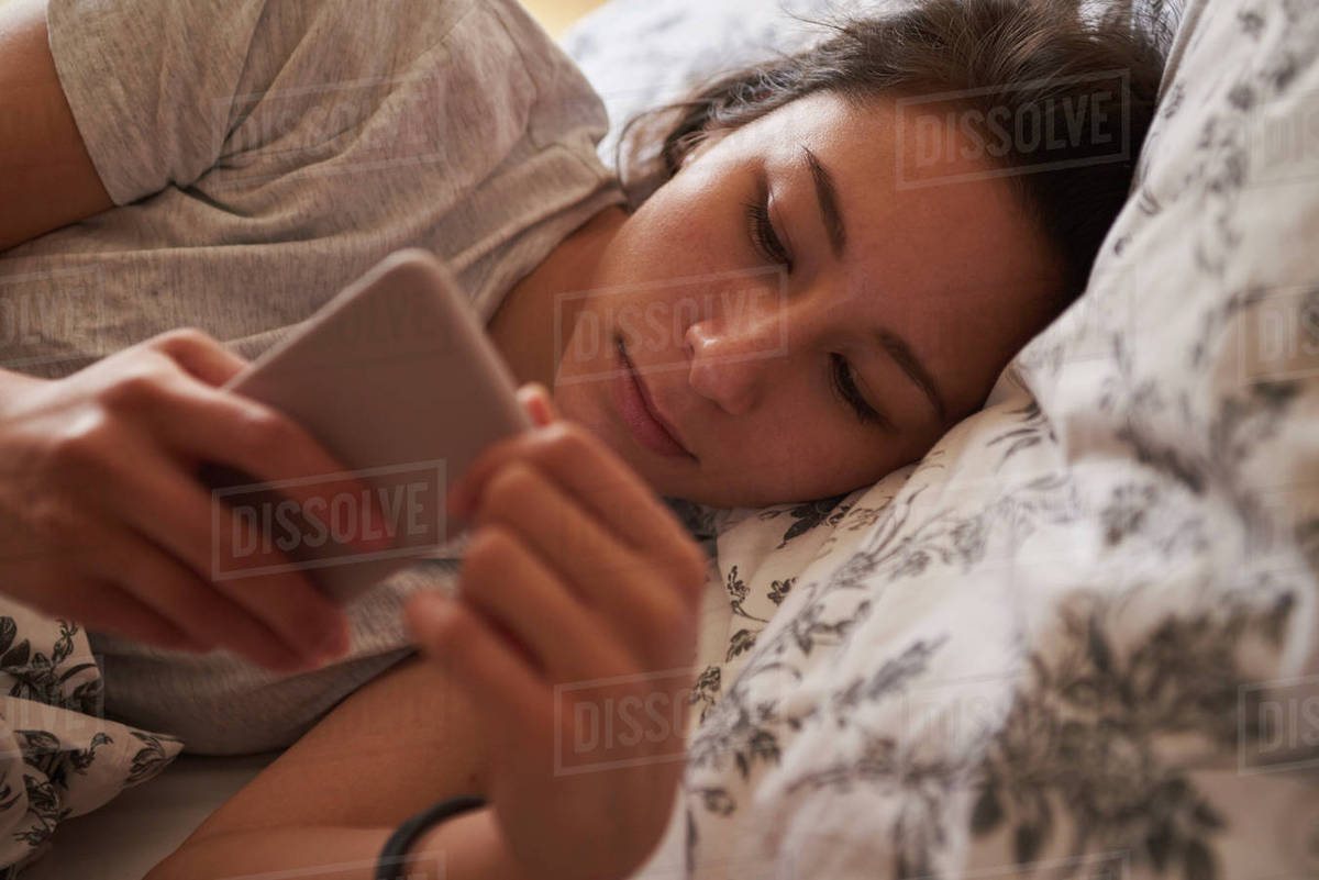Woman Waking In Bed And Checking Message On Mobile Phone Royalty-free stock photo