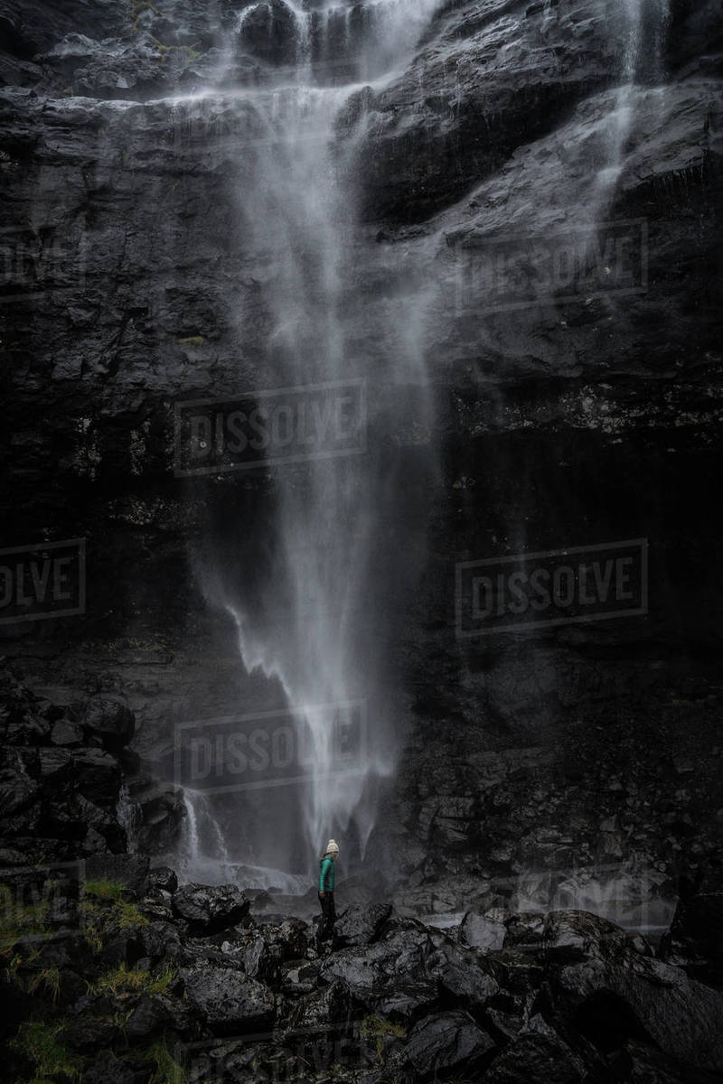 Woman standing on rock near waterfall, Faroe Islands, Denmark Royalty-free stock photo