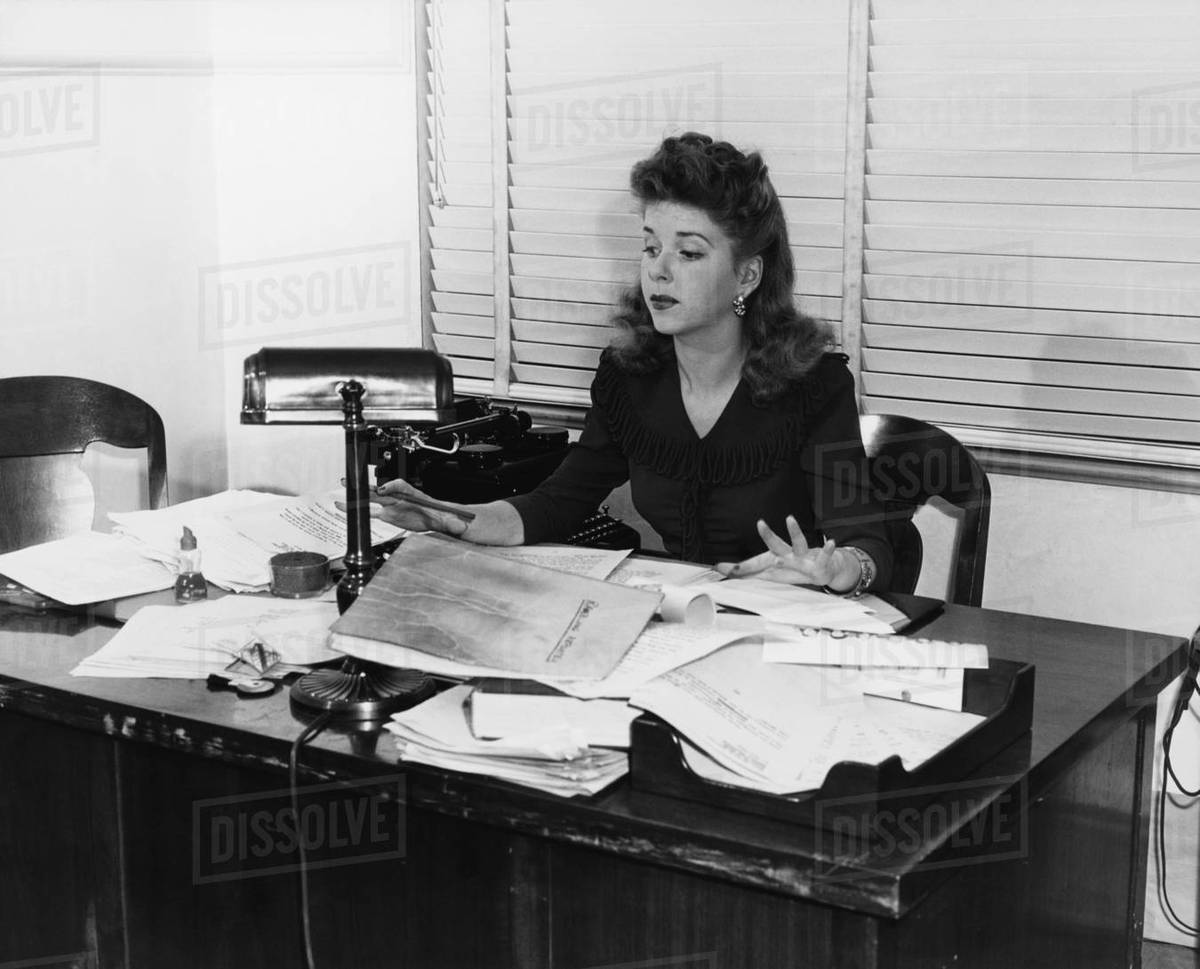 Woman working at desk covered in papers Royalty-free stock photo