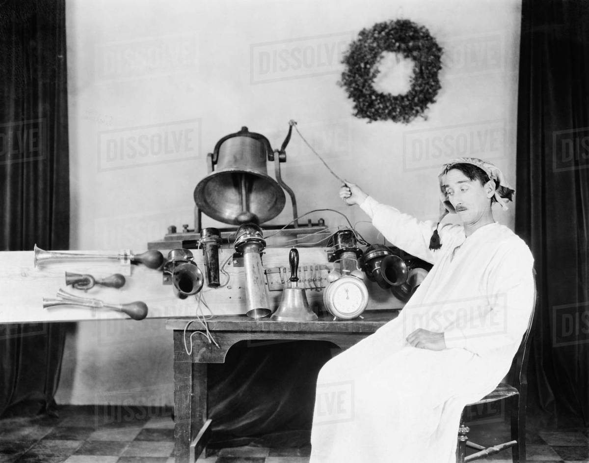 Man in a nightgown and sleeping cap ringing a big bell Stock Photo
