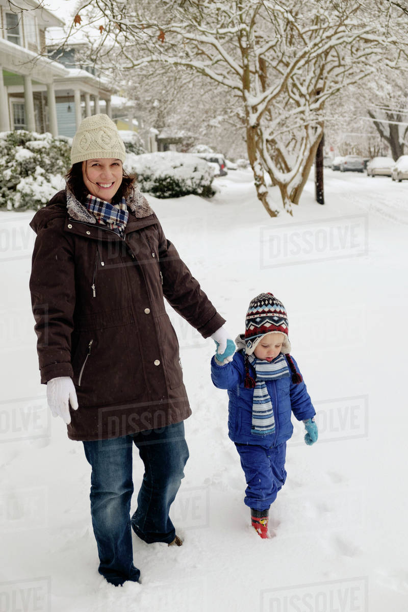 Caucasian mother and son walking in snow Stock Photo Dissolve