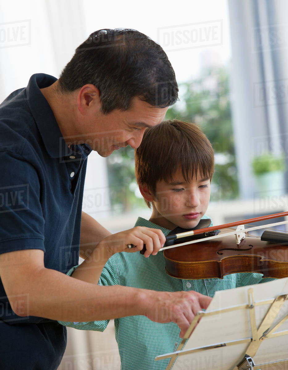 Father teaching son to play violin Stock Photo Dissolve