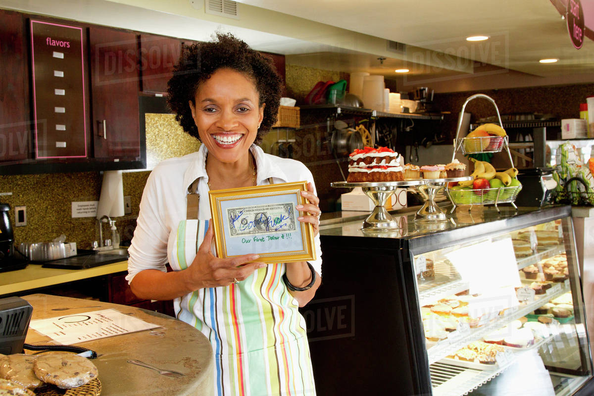 Bakery owner holding first dollar Stock Photo Dissolve