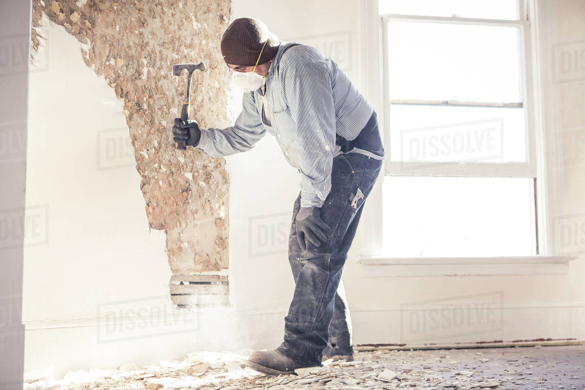 Hispanic construction worker hammering wall Royalty-free stock photo