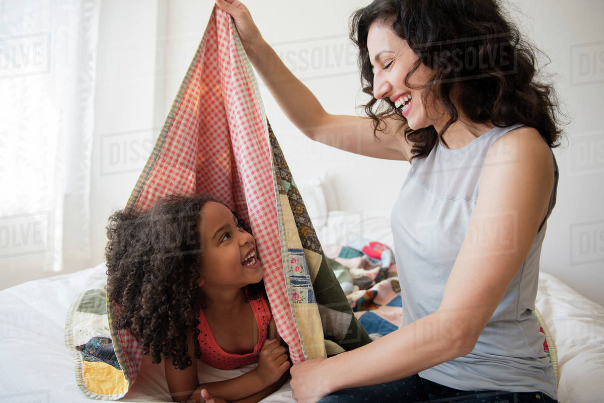 Mother and daughter playing in blanket fort Stock Photo Dissolve