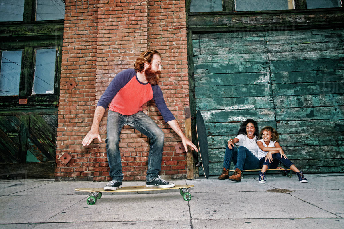 Family riding skateboards on sidewalk Stock Photo Dissolve