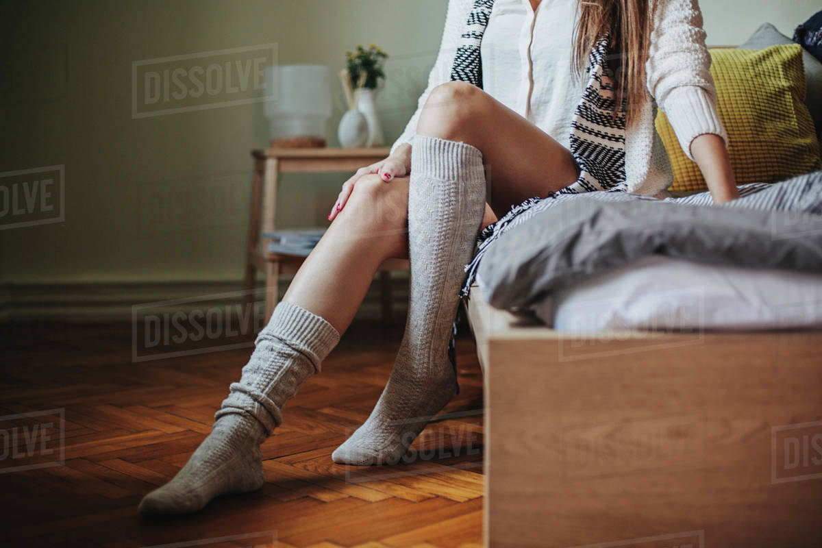Caucasian woman sitting on bed wearing socks Stock Photo Dissolve