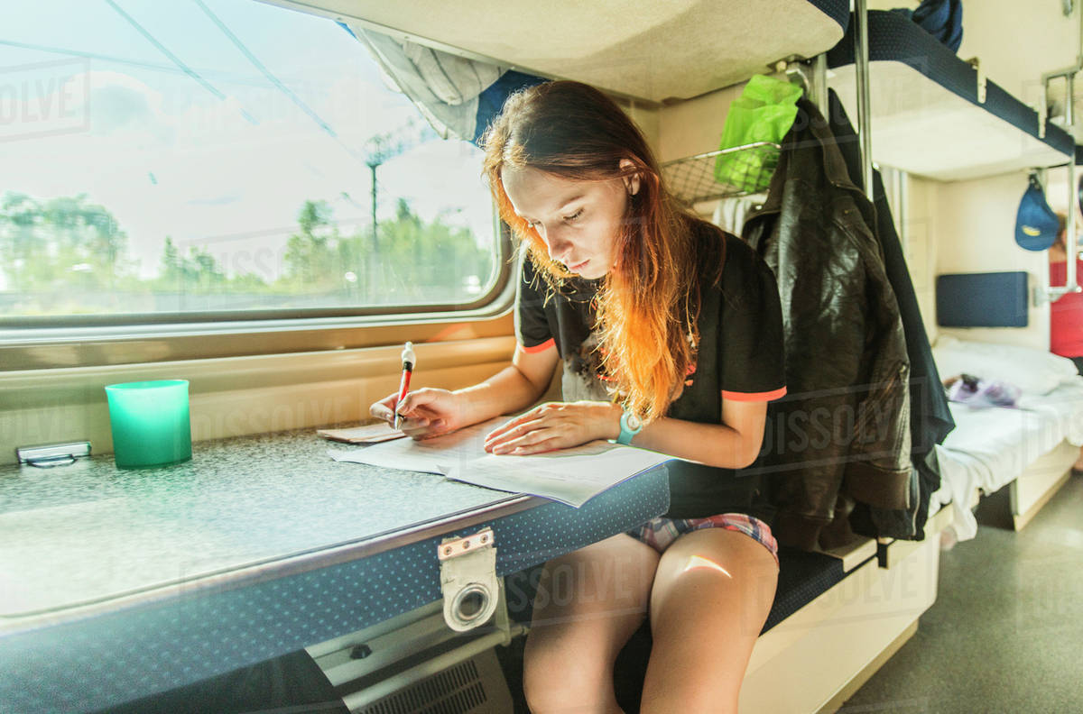 Caucasian girl writing on train - Royalty-free Stock Photo | Dissolve