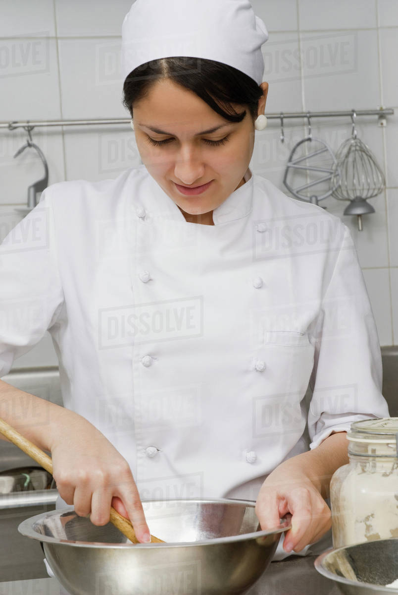 Baker stirring batter in bakery kitchen Stock Photo Dissolve