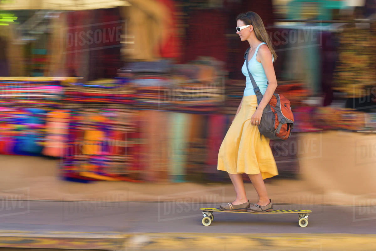 Caucasian woman skateboarding on sidewalk Stock Photo Dissolve