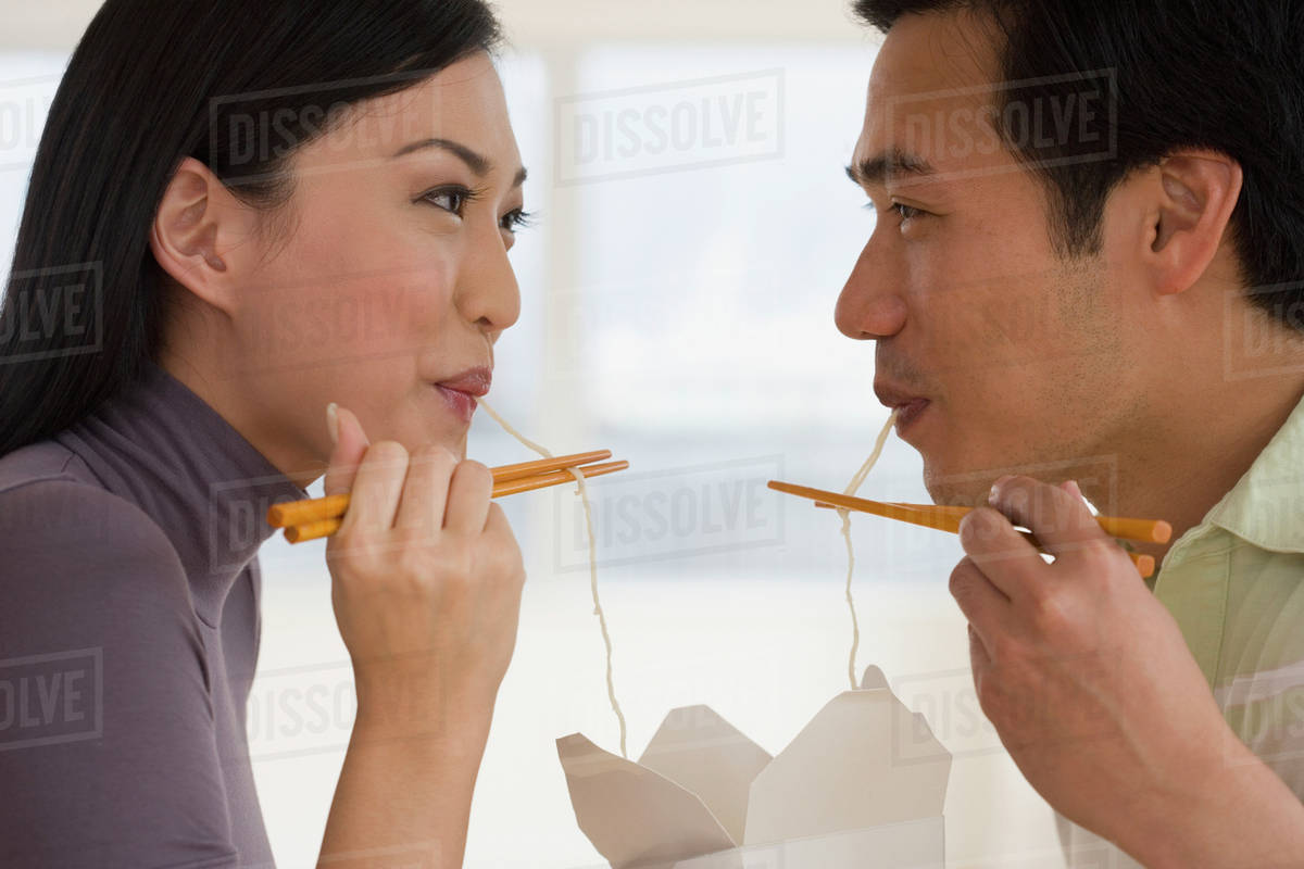 Asian couple eating noodles with chopsticks Stock Photo Dissolve