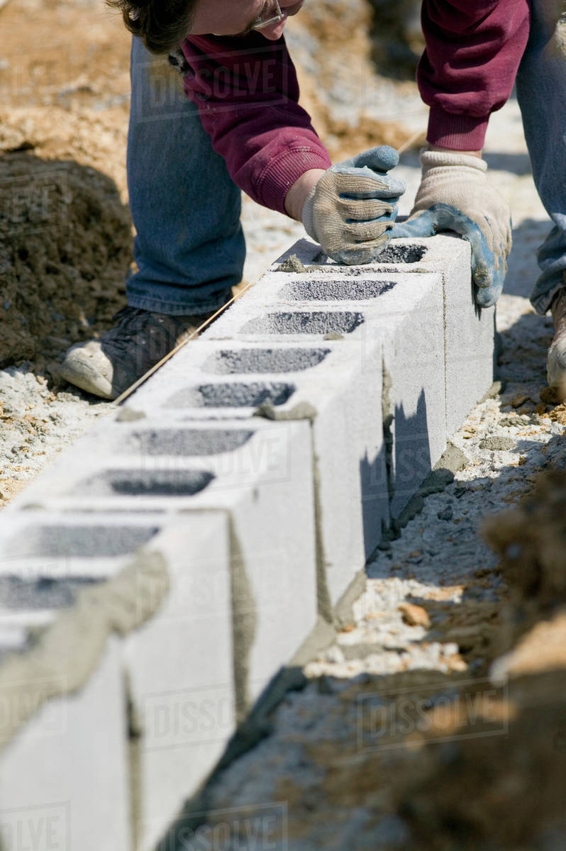 Worker filling cinder blocks with mortar Stock Photo Dissolve