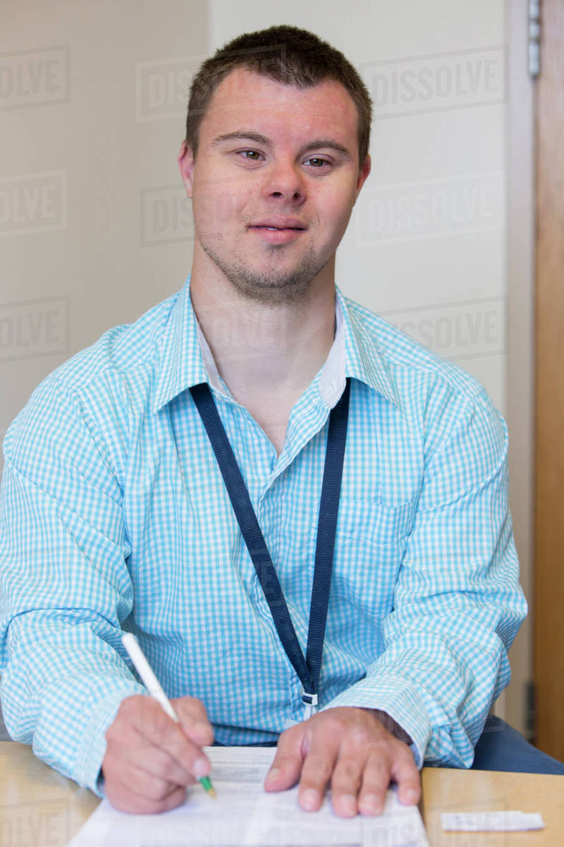 Caucasian man with Down Syndrome writing notes at desk Stock Photo