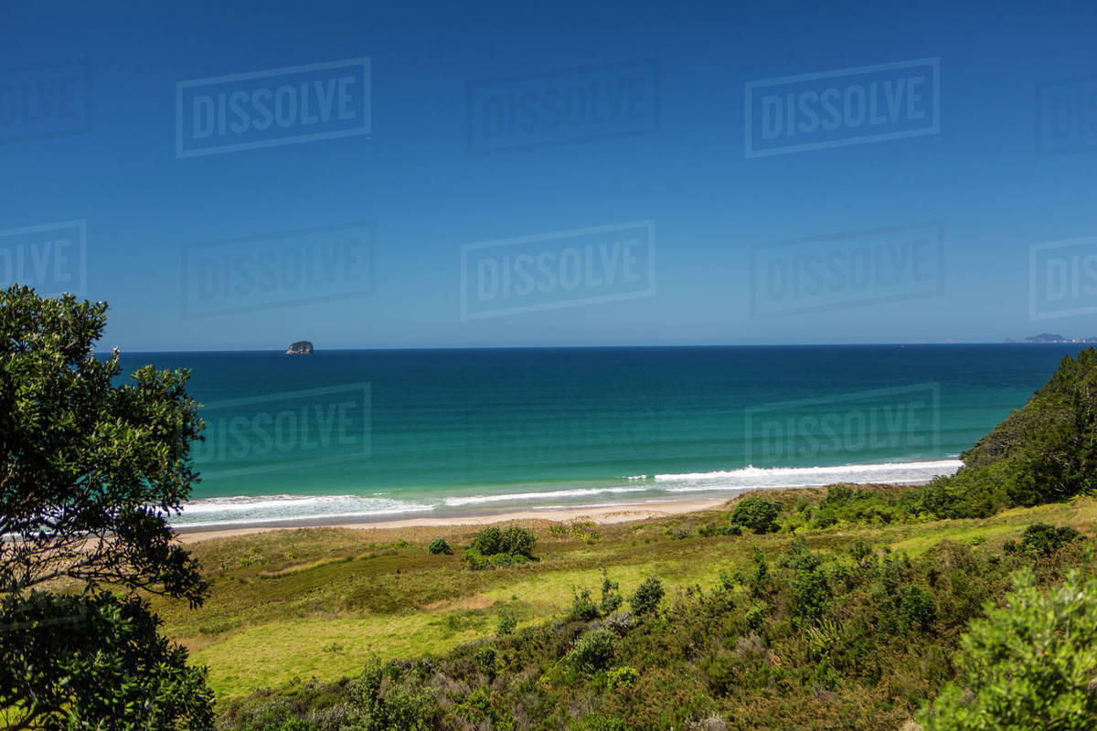 Hillside and remote beach under blue sky Stock Photo Dissolve