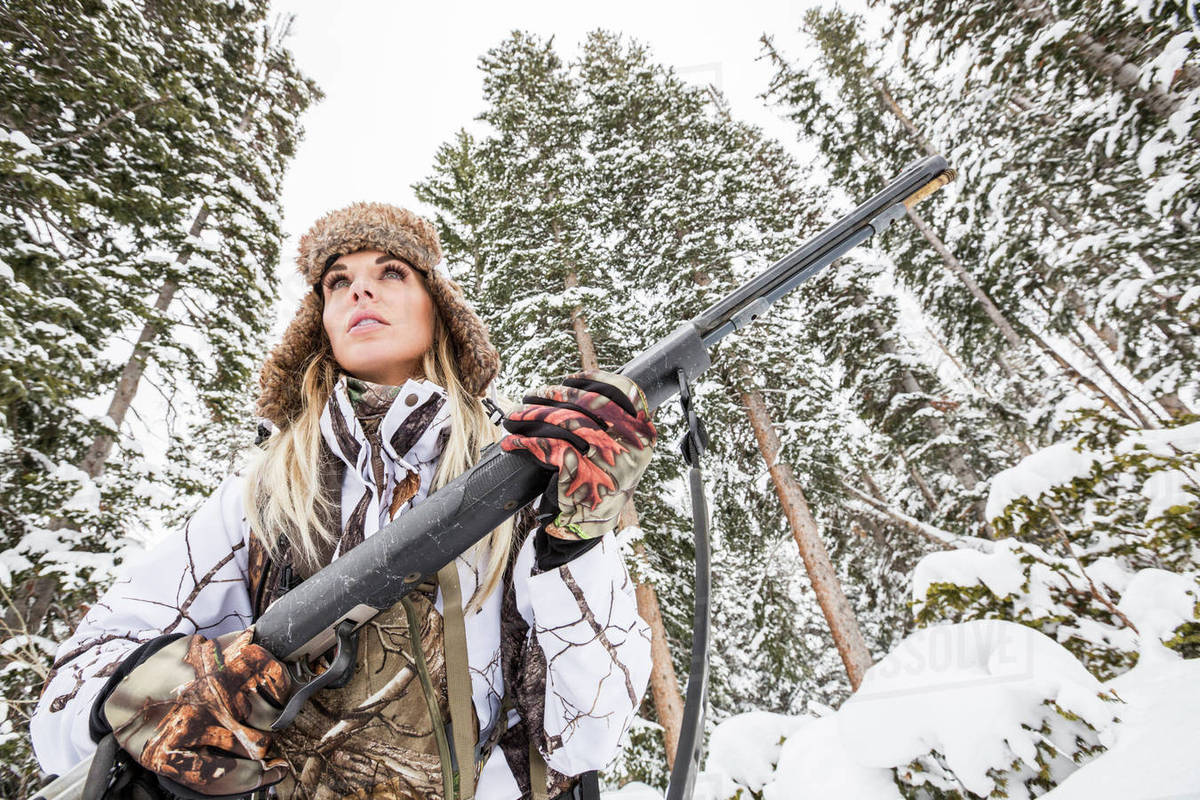Caucasian woman hunting in forest holding rifle Stock Photo Dissolve