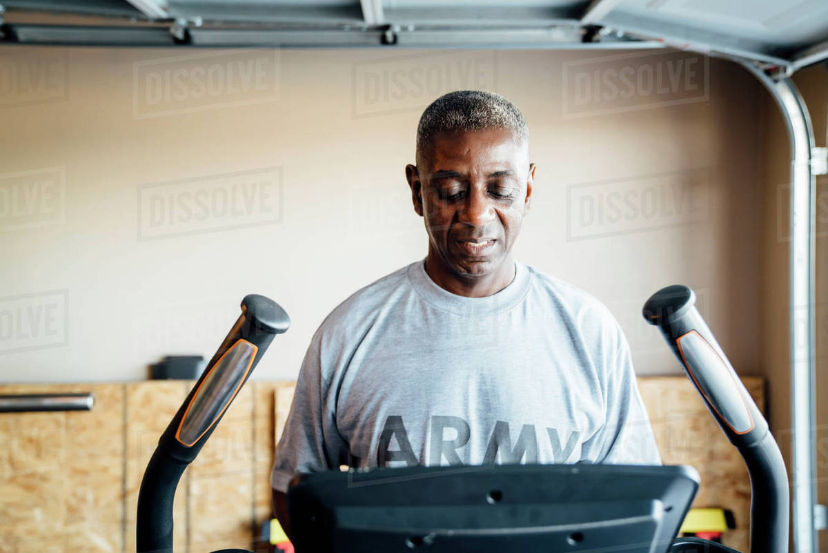 Black man using treadmill in garage Stock Photo Dissolve