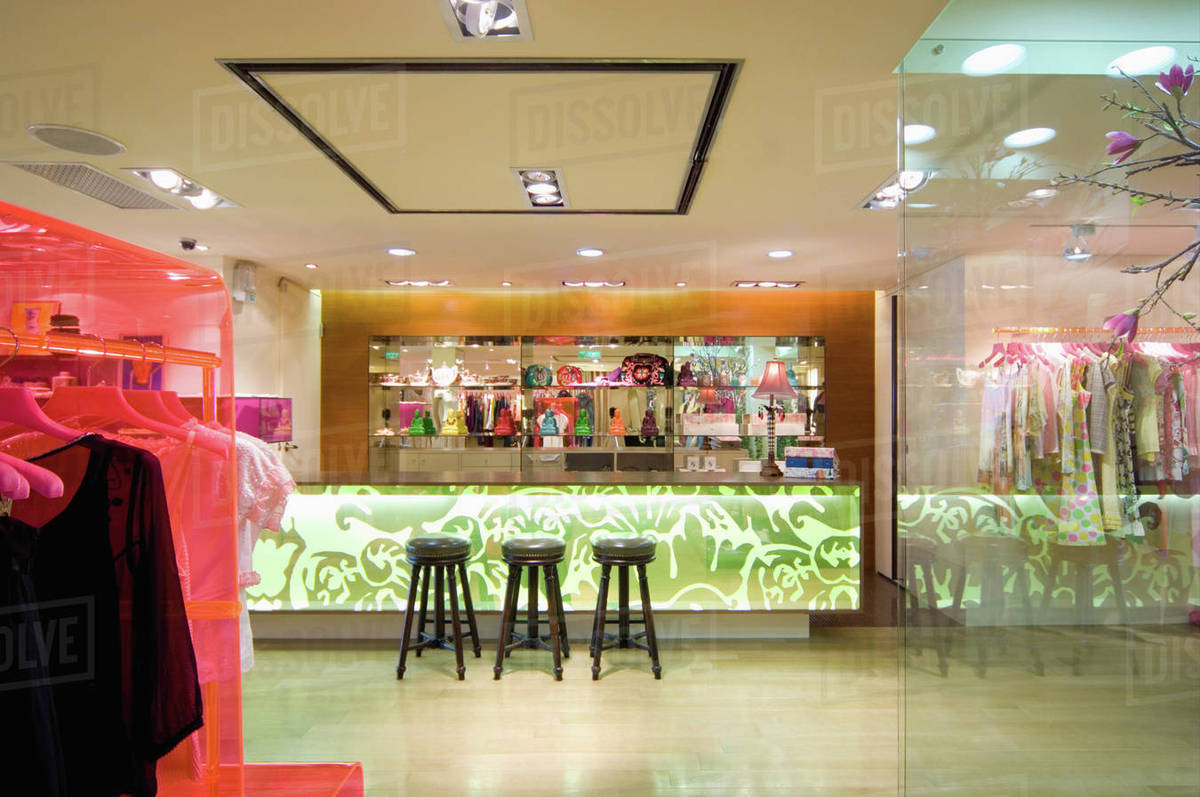 Barstools by lit counter in modern clothing store Stock Photo Dissolve