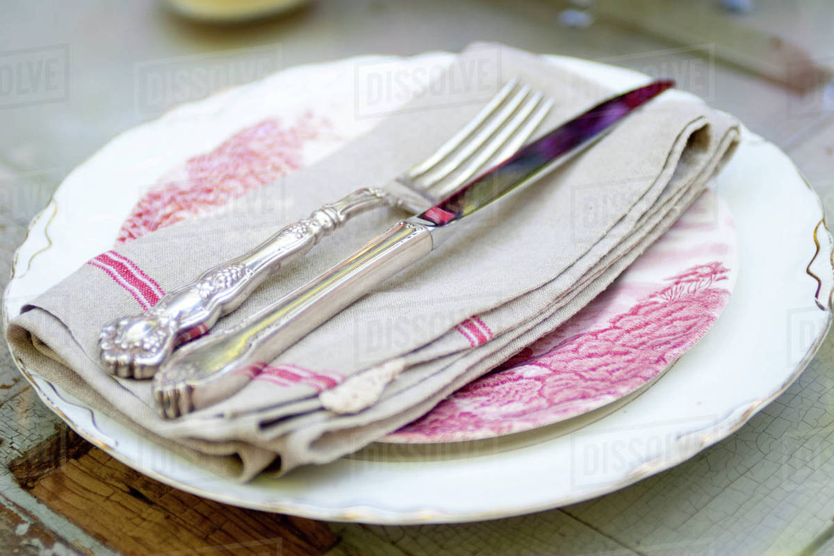 Silverware and napkin on plate Stock Photo Dissolve