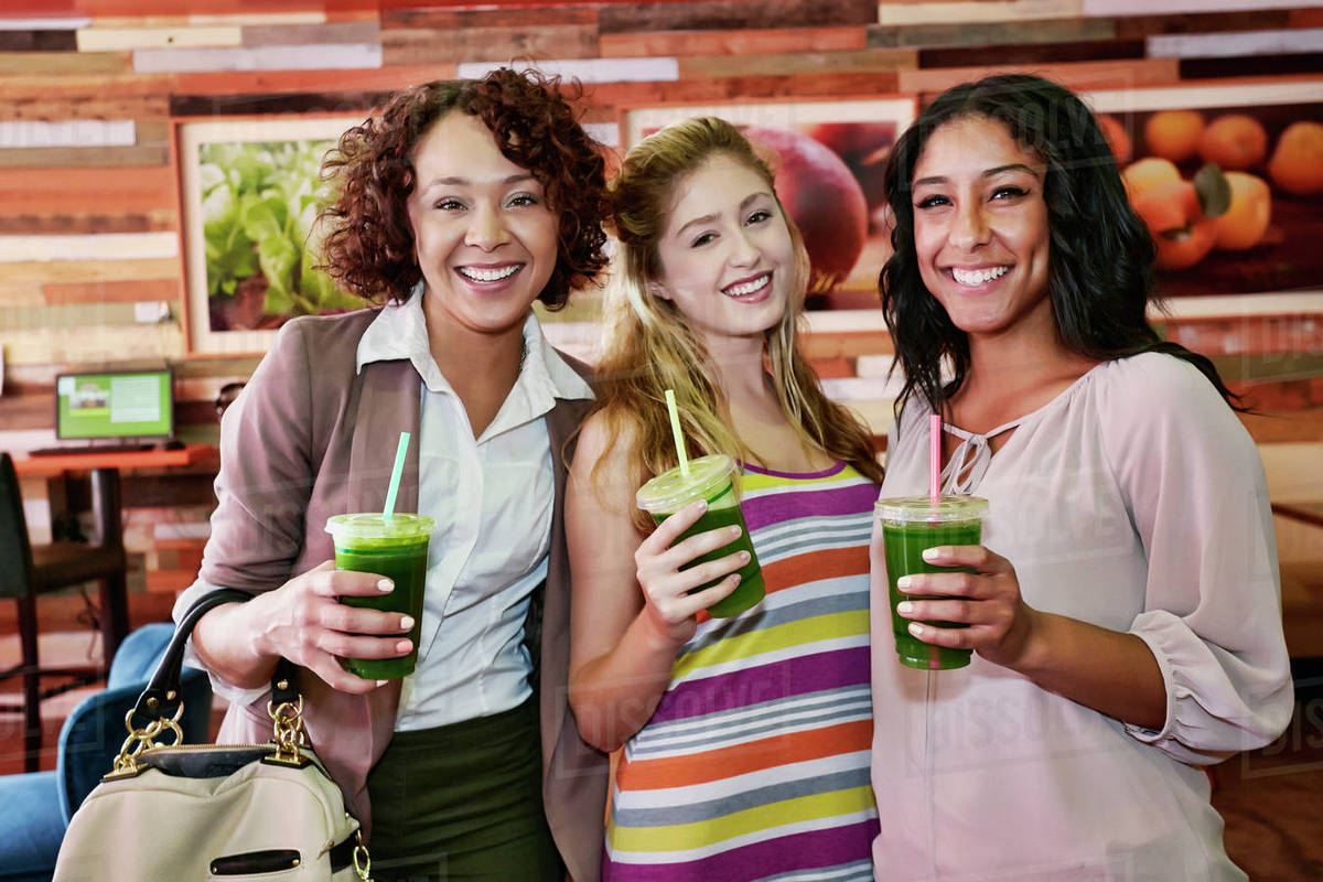 Women having juice together in cafe Stock Photo Dissolve