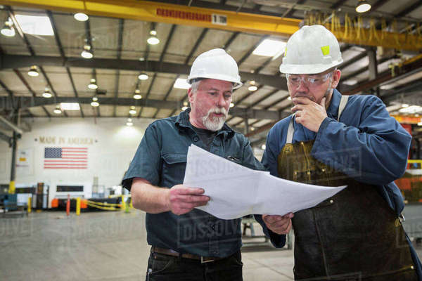 Workers examining paperwork in factory - Stock Photo - Dissolve