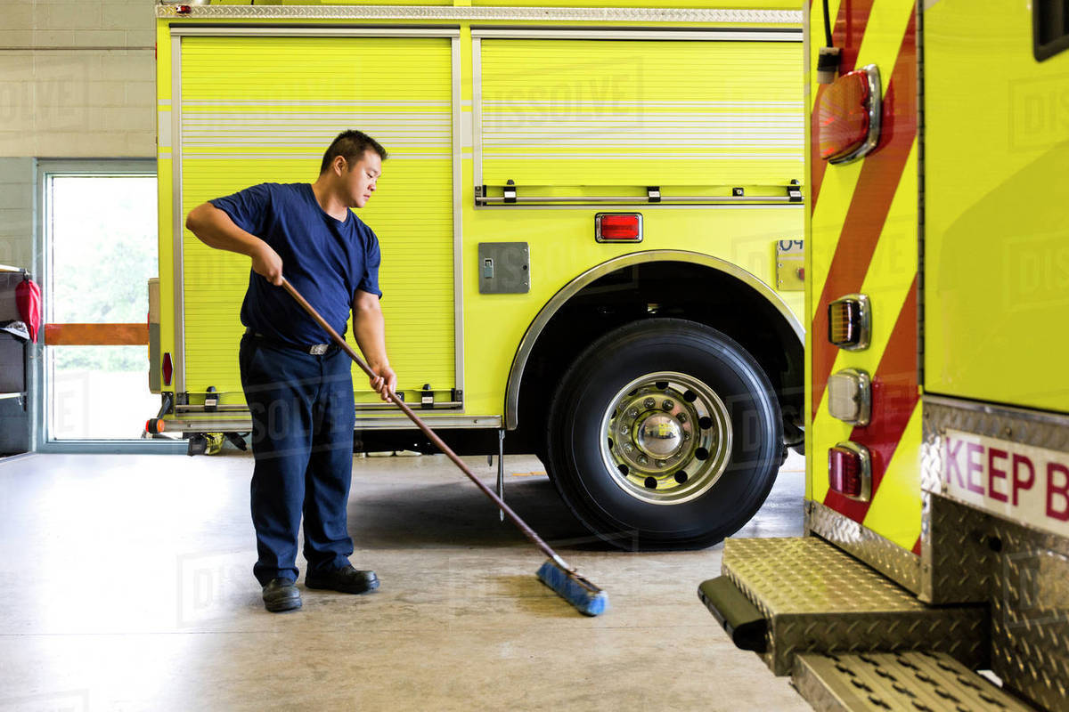 Chinese fireman sweeping floor near fire trucks - Royalty-free Stock Photo  | Dissolve