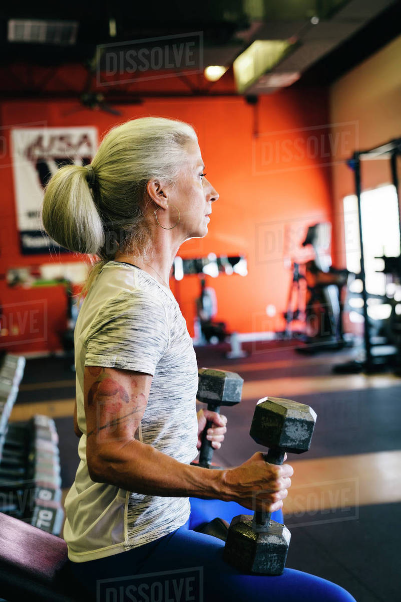Woman lifting dumbbells in gymnasium Stock Photo Dissolve