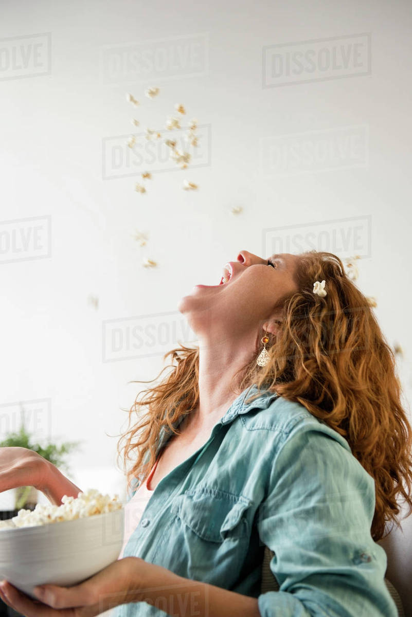 Caucasian woman throwing popcorn into mouth Stock Photo Dissolve