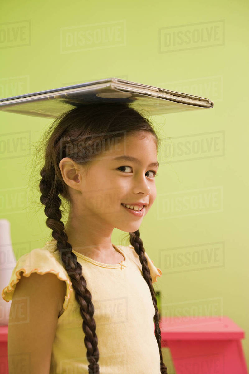 Pacific Islander girl balancing book on head Stock Photo Dissolve