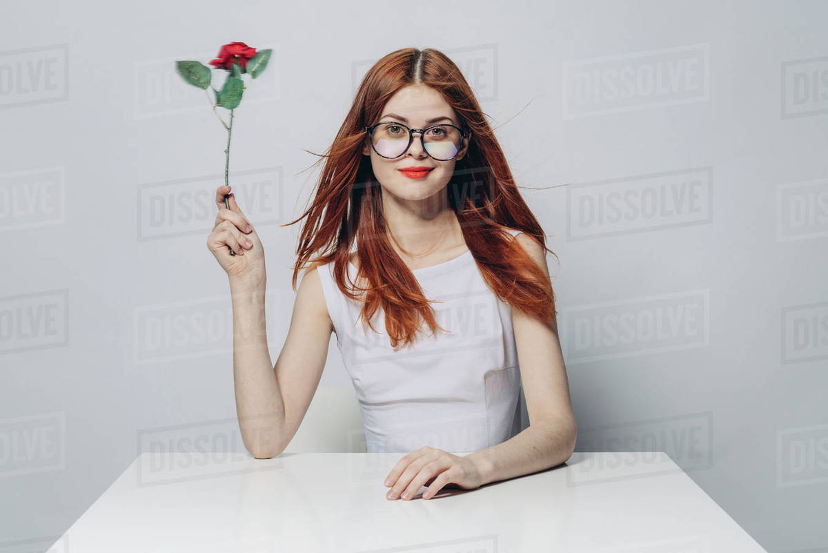 Caucasian woman sitting at windy table holding rose - Royalty-free ...