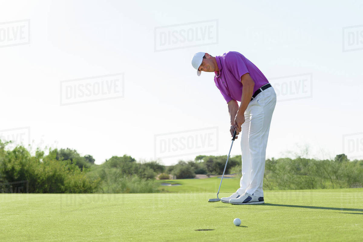 Hispanic golfer putting on golf course Stock Photo Dissolve