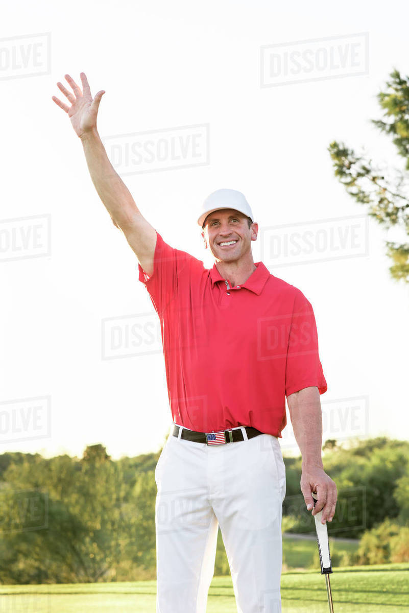 Hispanic golfer waving on golf course Stock Photo Dissolve