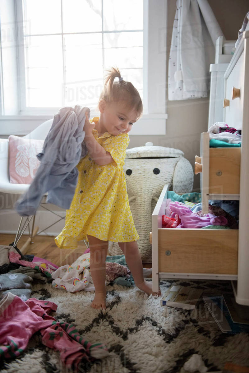Caucasian baby girl removing clothing from dresser drawer Stock Photo