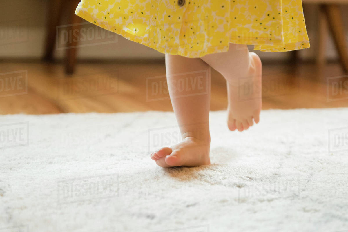 Barefoot Caucasian baby girl walking on rug Stock Photo Dissolve