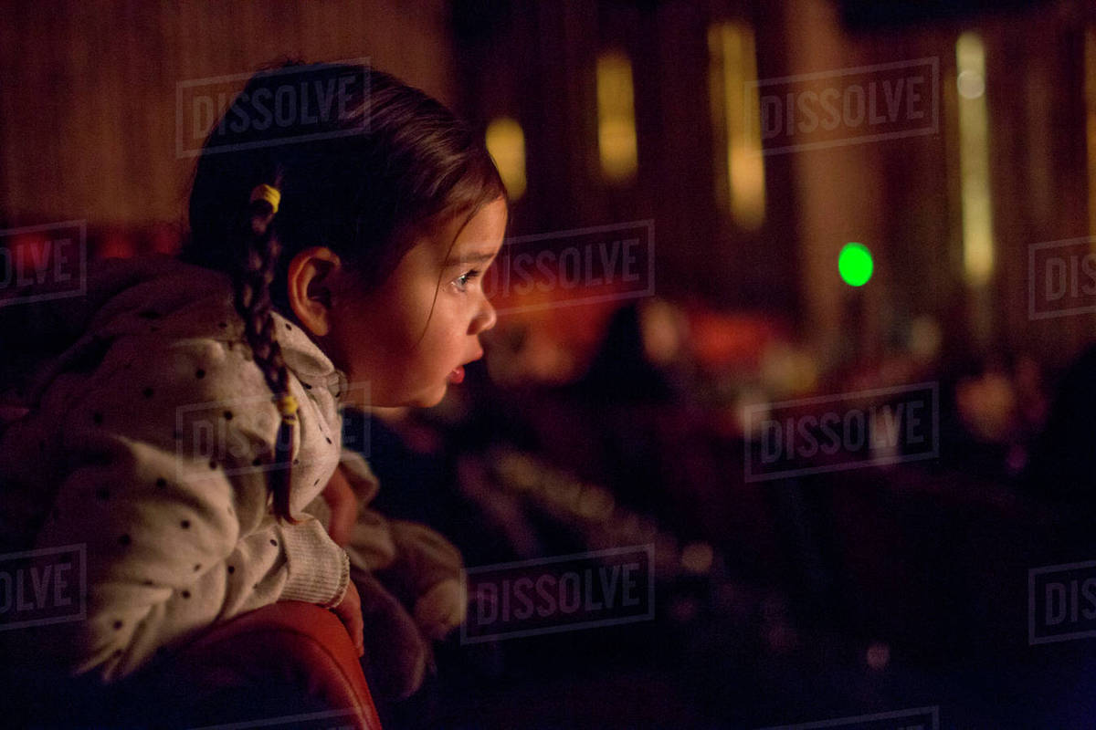 Mixed Race girl leaning on chair watching movie in theater Royalty-free stock photo