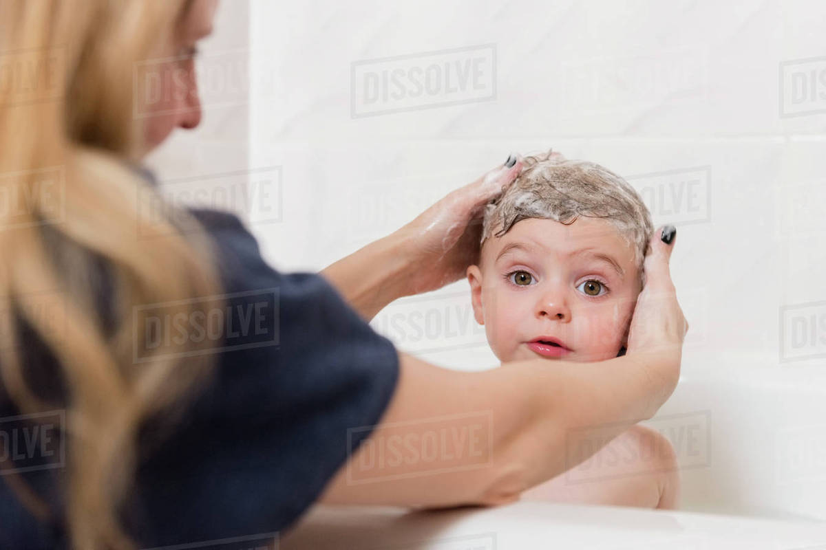 Caucasian Mother Washing Hair Of Girl In Bathtub Stock Photo