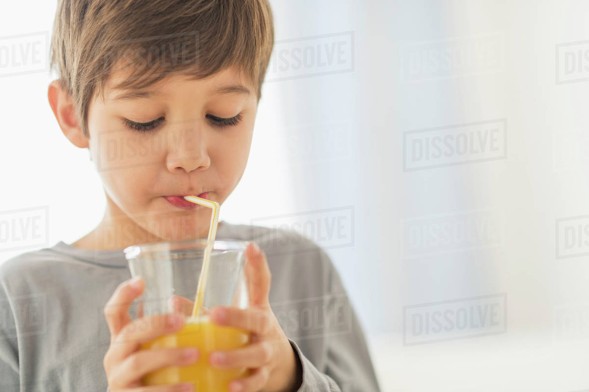 Hispanic boy drinking juice with straw Stock Photo Dissolve