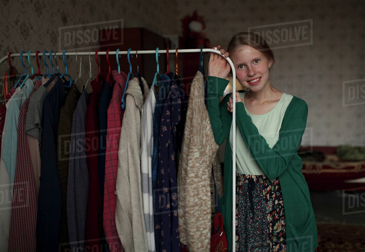 Portrait of pensive Caucasian woman leaning on clothing rack Stock