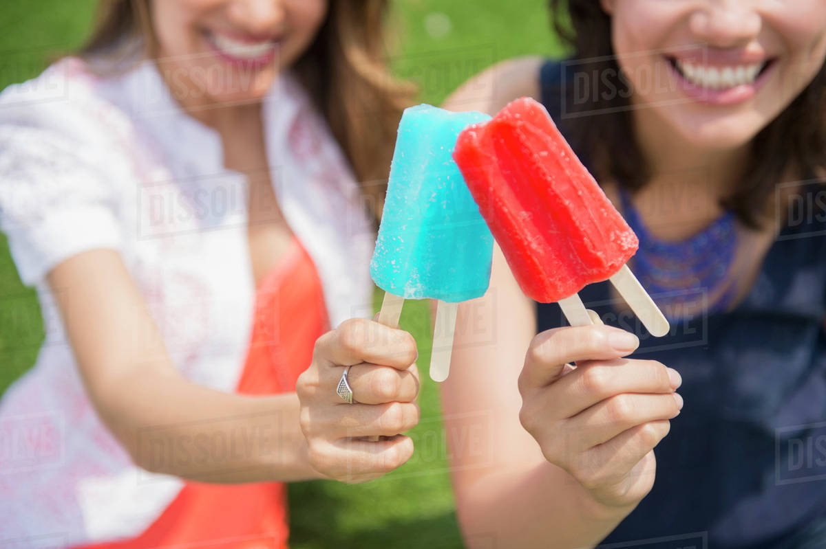 Hispanic women eating popsicles outdoors Stock Photo Dissolve