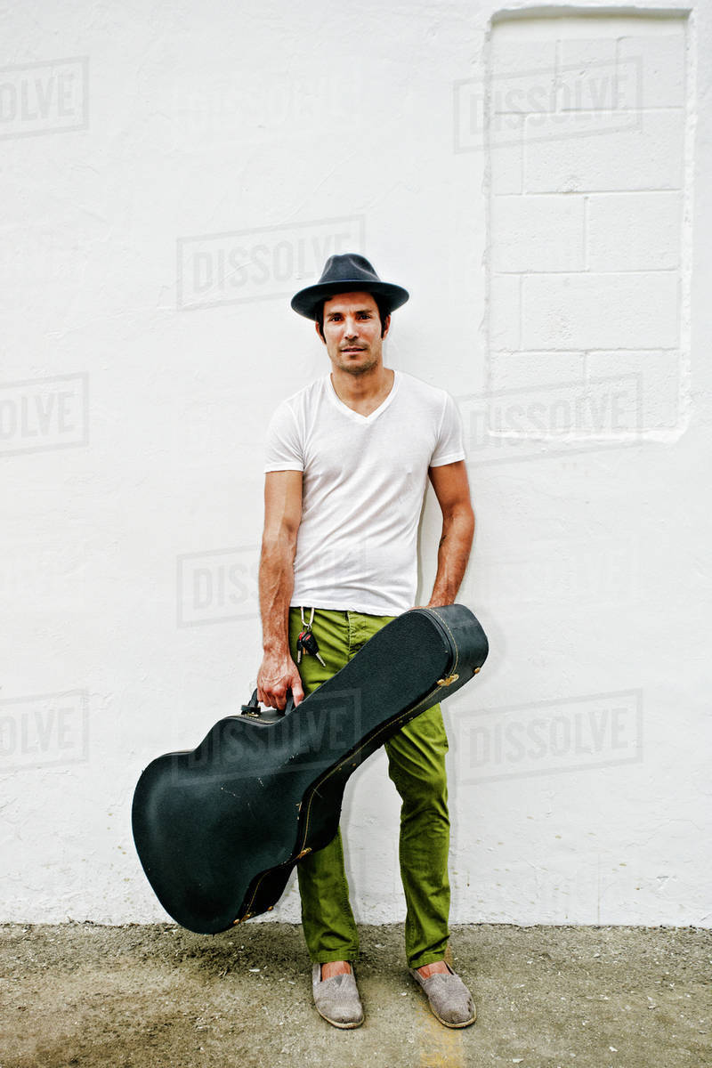 Mixed race musician carrying guitar case Stock Photo Dissolve