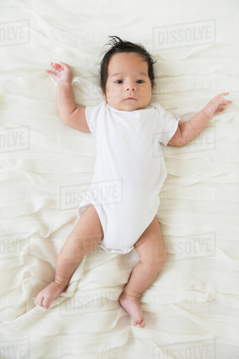 Hispanic infant laying on blanket Stock Photo Dissolve