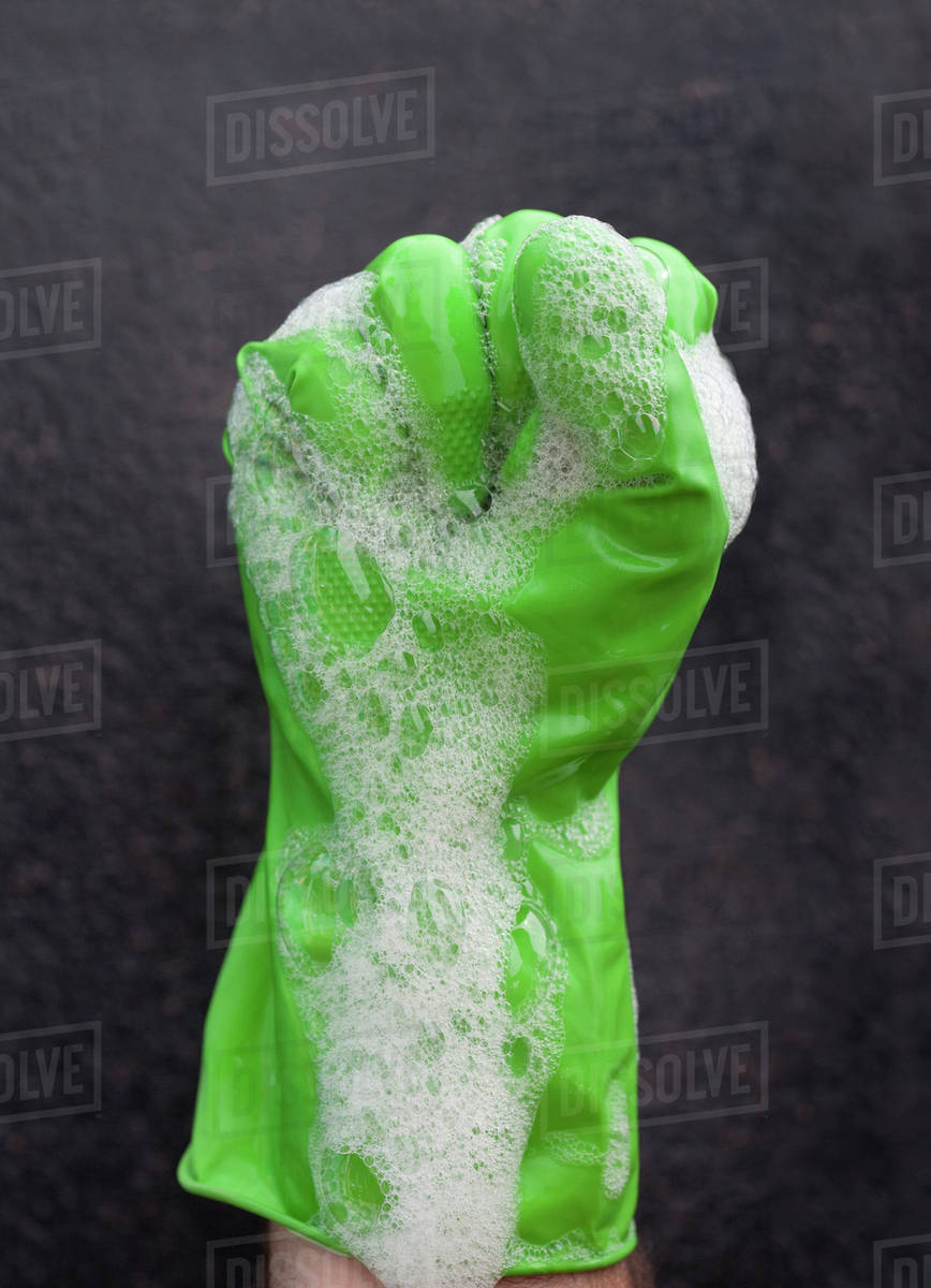 Close up of soap suds covering rubber glove Stock Photo Dissolve