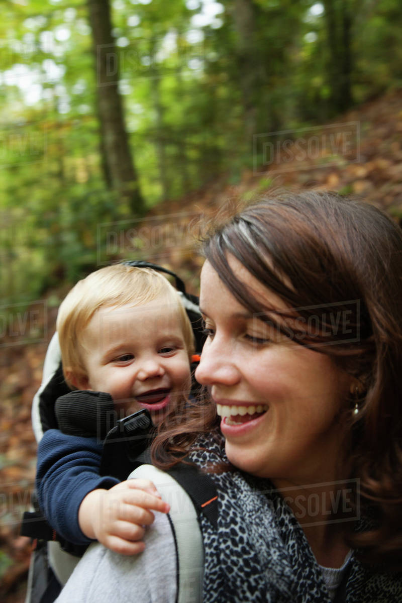 Caucasian mother carrying toddler on back Stock Photo Dissolve