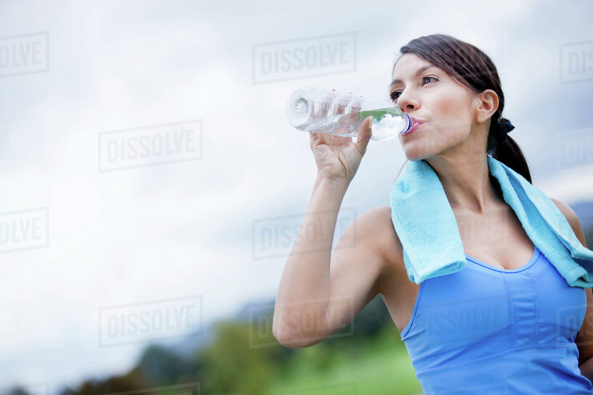 Woman drinking water after exercise Stock Photo Dissolve