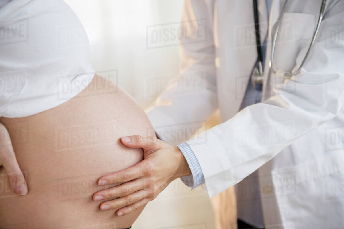 Doctor examining belly of pregnant woman Stock Photo Dissolve