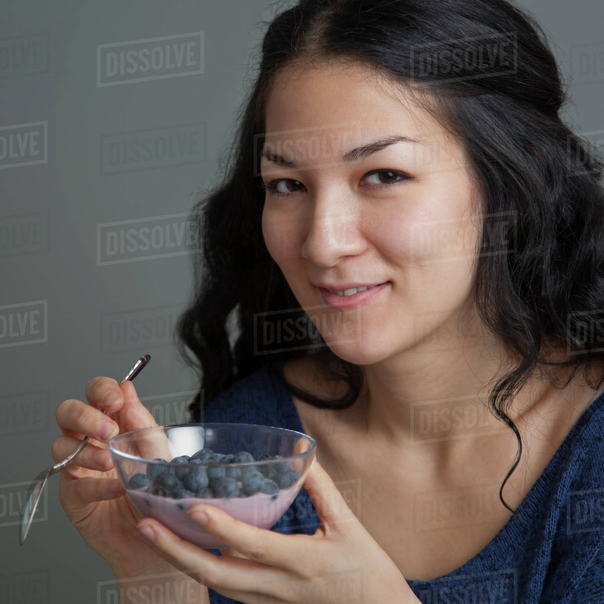 Mixed race woman eating yogurt and fruit Stock Photo Dissolve