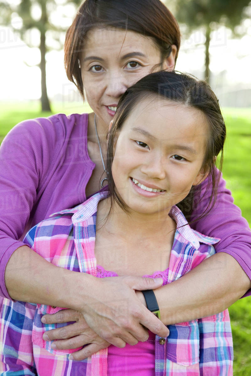 Chinese mother hugging daughter outdoors Stock Photo Dissolve